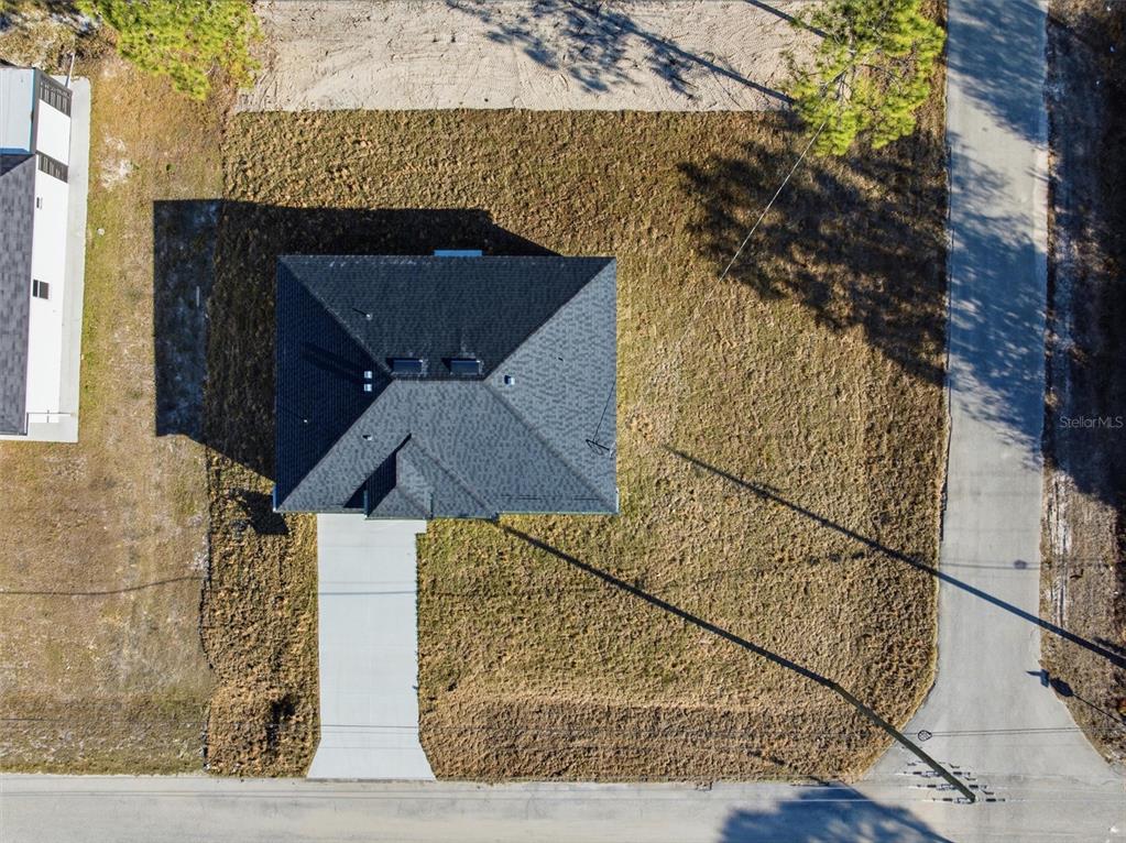 An aerial view shows a house with a dark roof, a driveway, and surrounding yard — 107 E 15TH STREET, LEHIGH ACRES, FL