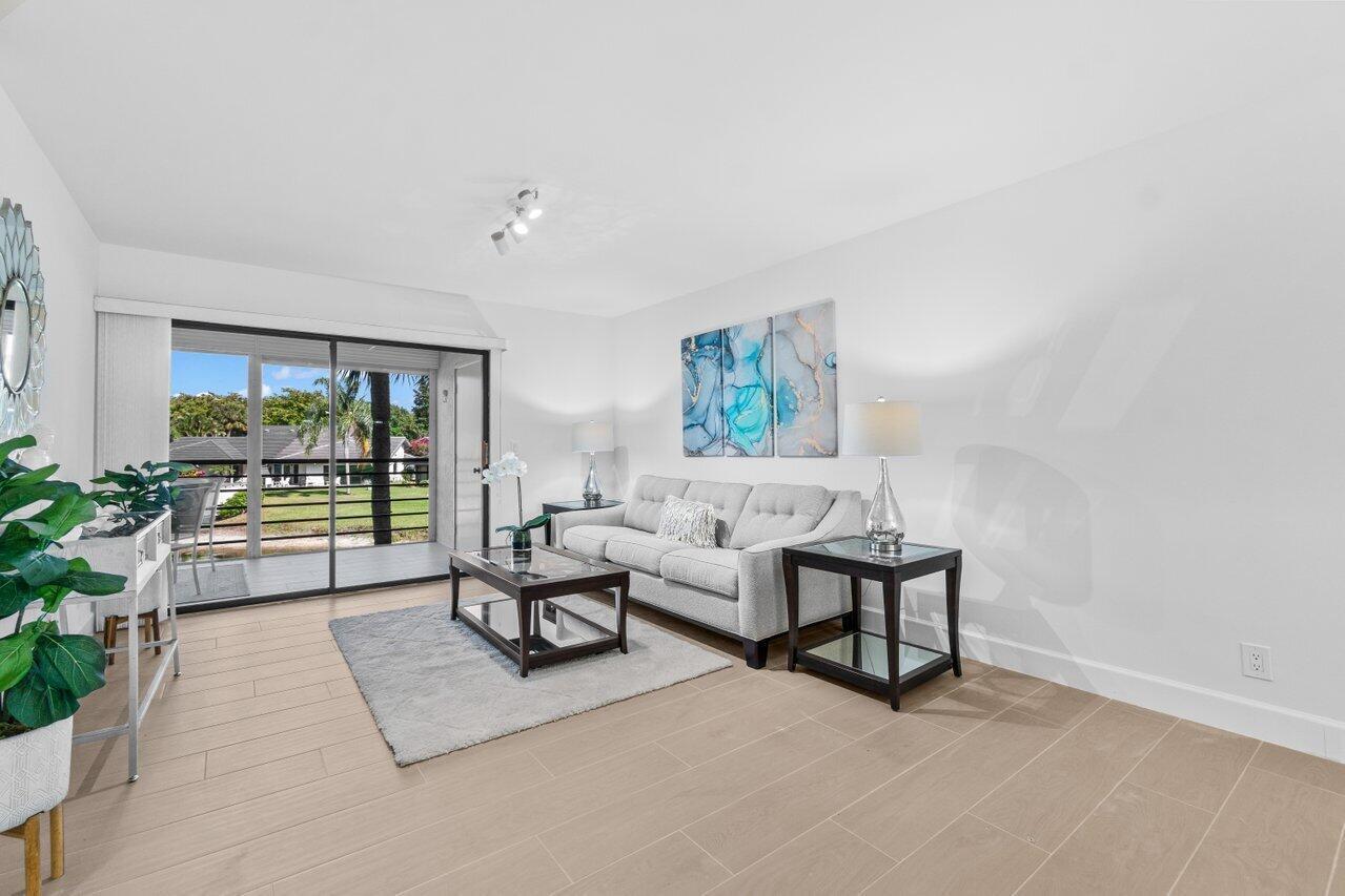 A living room features light tile floors, a gray sofa, and a sliding glass door — 10092 Cedar Point Boulevard # 204, Boynton Beach FL 33437, BOYNTON BEACH, FL