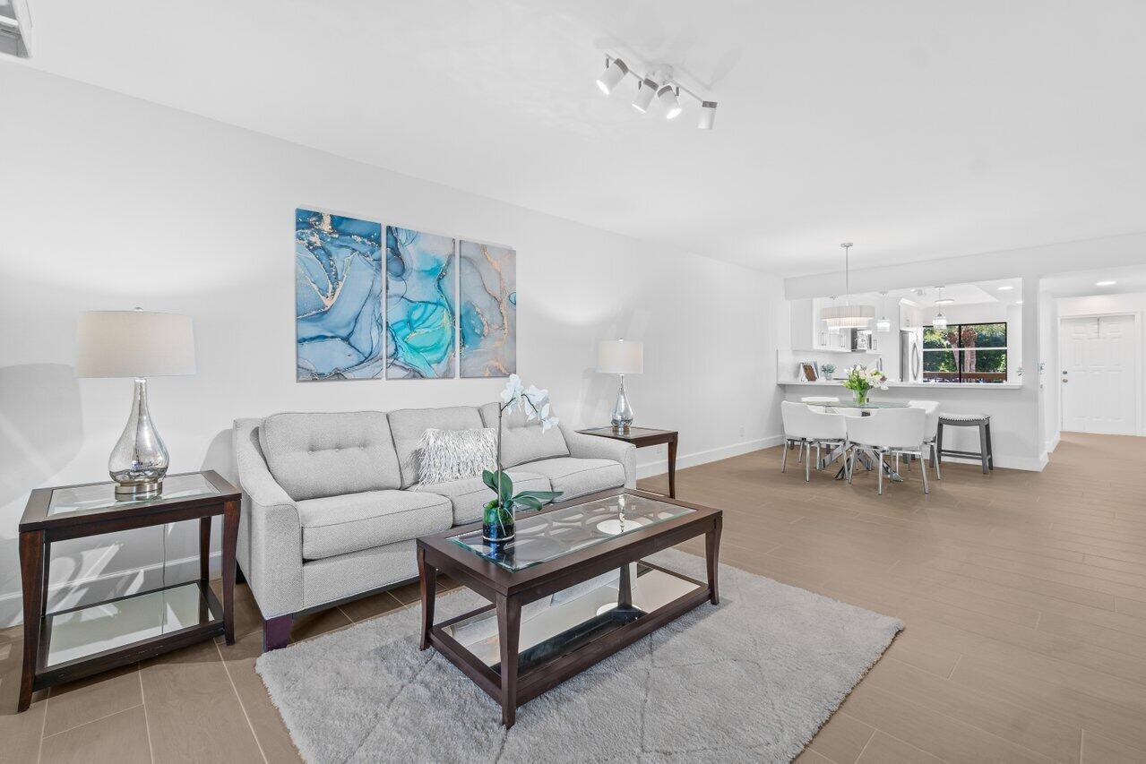 A living room with a grey sofa, glass-topped tables, and an adjacent dining area — 10092 Cedar Point Boulevard # 204, Boynton Beach FL 33437, BOYNTON BEACH, FL