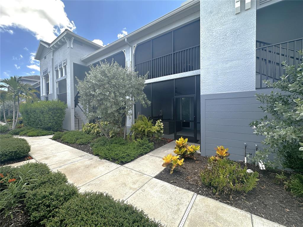 A concrete walkway leads to the screened-in patio of a multi-story residential building — 14050 HERITAGE LANDING BOULEVARD UNIT 225, PUNTA GORDA, FL