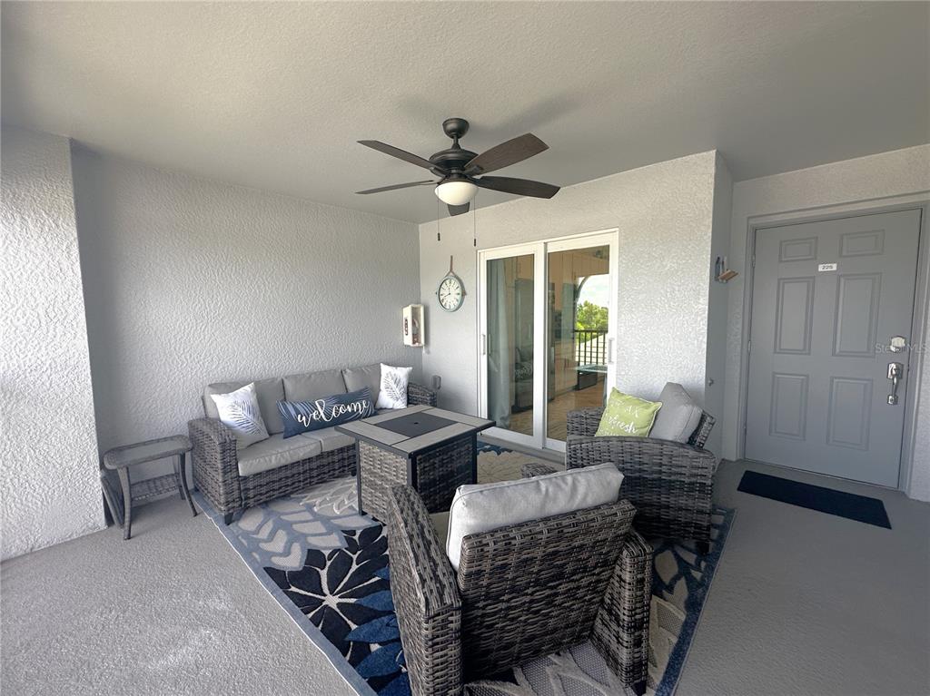 A covered balcony features wicker patio furniture, a ceiling fan, and a sliding glass door — 14050 HERITAGE LANDING BOULEVARD UNIT 225, PUNTA GORDA, FL