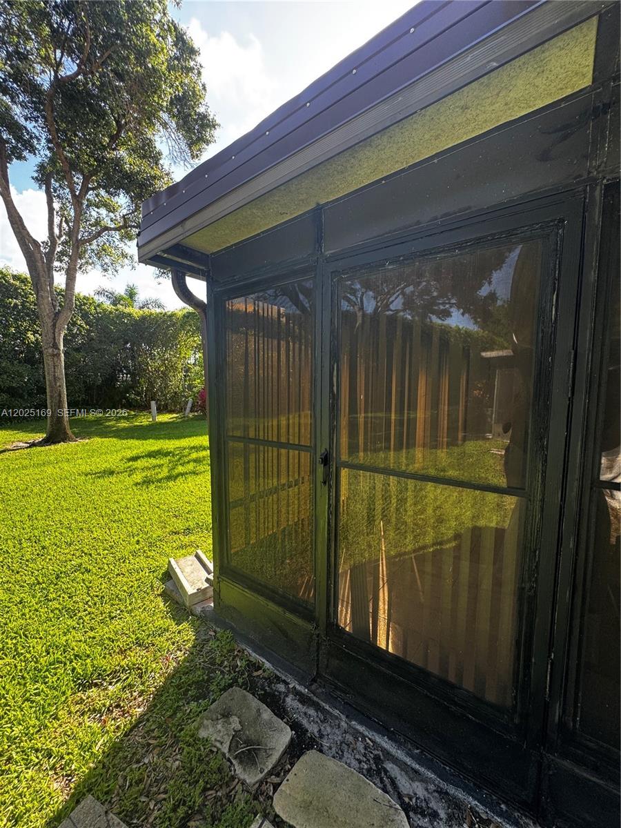 A black-framed screened-in porch exterior stands beside a grassy yard with trees — 9699 Pavarotti Ter # 103, Boynton Beach FL 33437, BOYNTON BEACH, FL