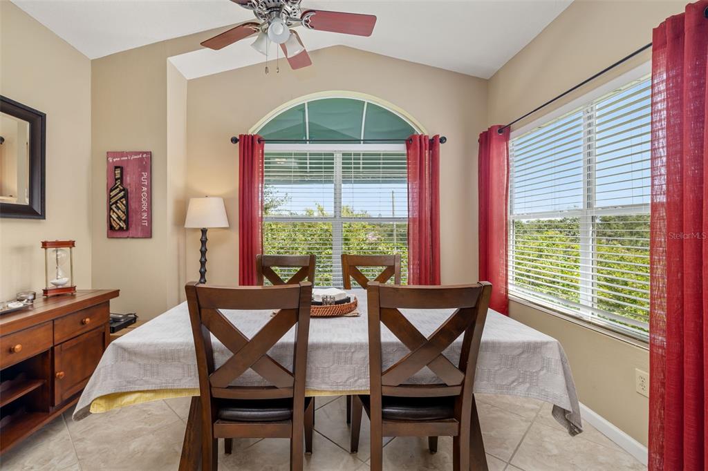 A dining room features a wooden table with chairs, a ceiling fan, and large windows — 10764 70TH AVENUE UNIT 1304, SEMINOLE, FL