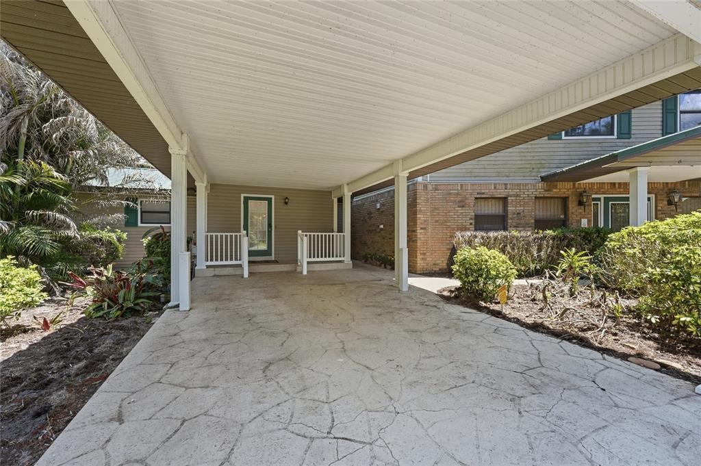 A covered carport with a concrete floor leads to a front door with white railings — 200 WINDY POINT ROAD, LAKE PLACID, FL