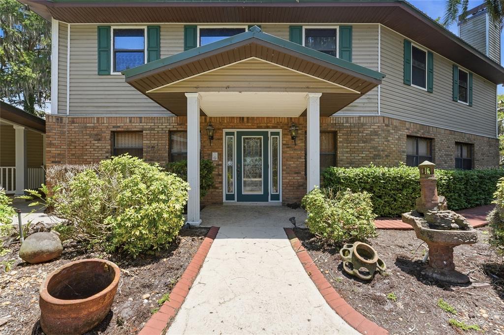 A concrete walkway leads to the front entrance of a two-story brick and siding house — 200 WINDY POINT ROAD, LAKE PLACID, FL