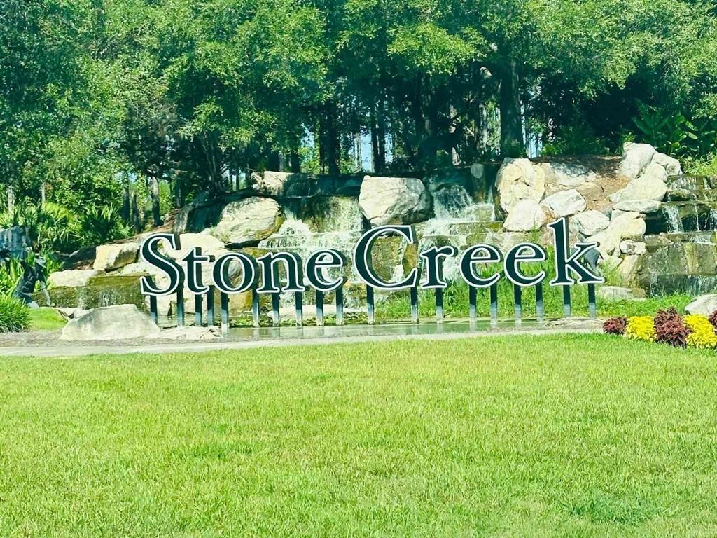 A stone waterfall feature with the text Stone Creek sits behind a grassy lawn — 9335 SW 53RD PLACE, OCALA, FL