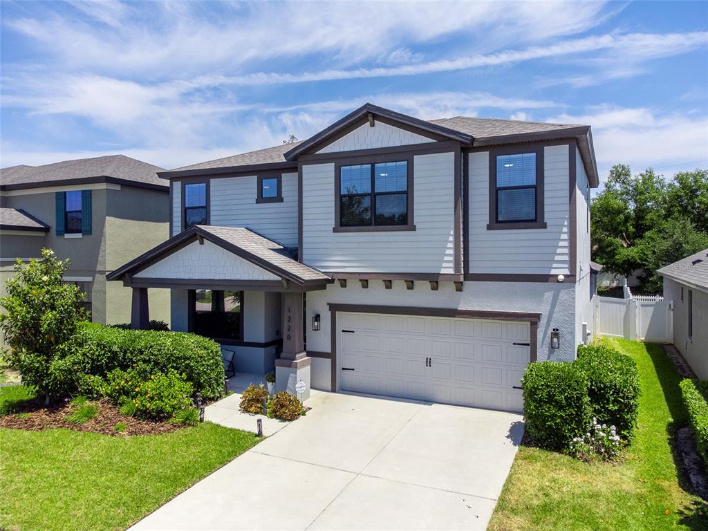 A two-story house with light gray siding, a two-car garage, and a front porch — 1220 FLORABLU DRIVE, SEFFNER, FL