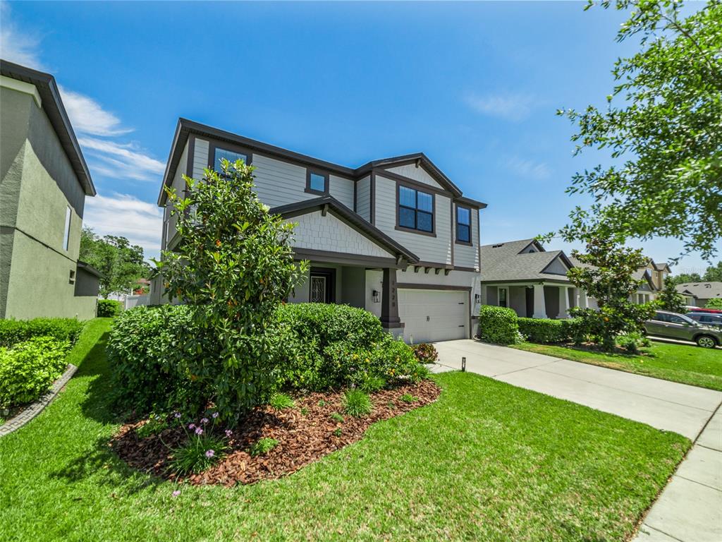 A two-story suburban house with a beige exterior, a front porch, and a concrete driveway — 1220 FLORABLU DRIVE, SEFFNER, FL