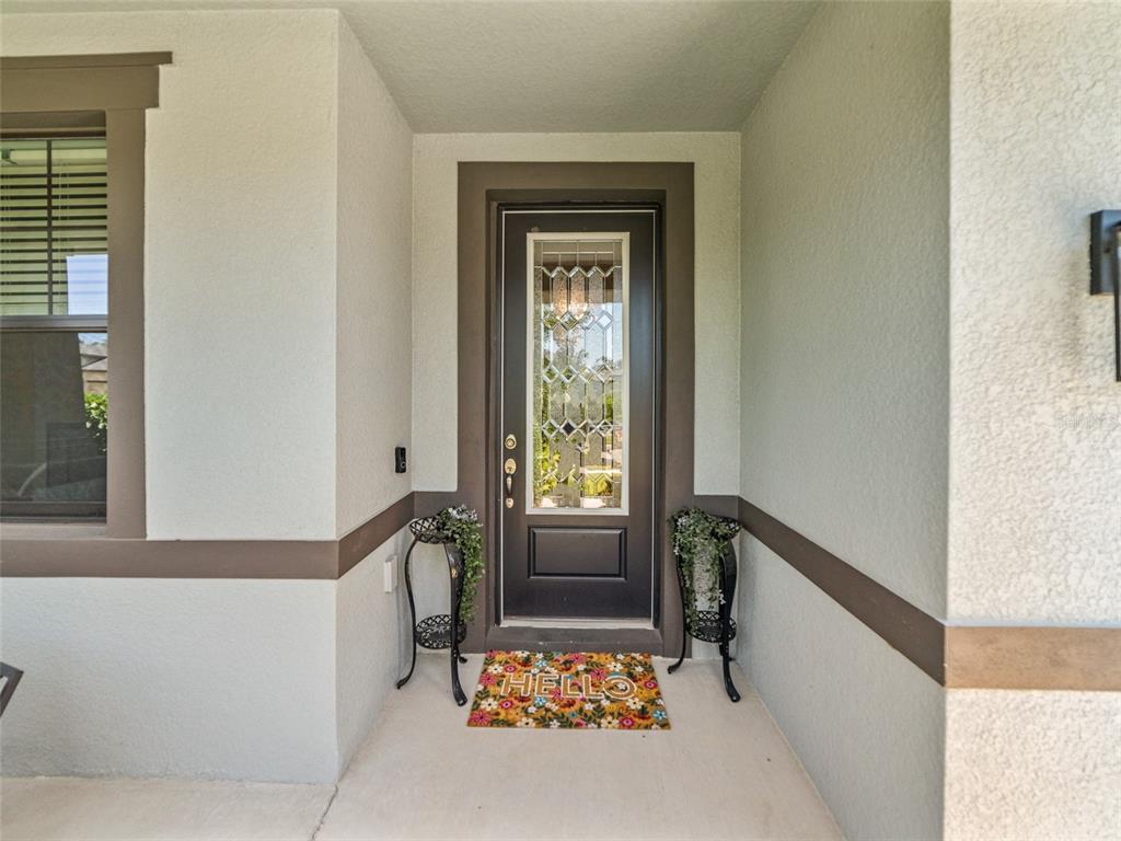 A front entryway features a dark door with a glass insert and a floral doormat — 1220 FLORABLU DRIVE, SEFFNER, FL