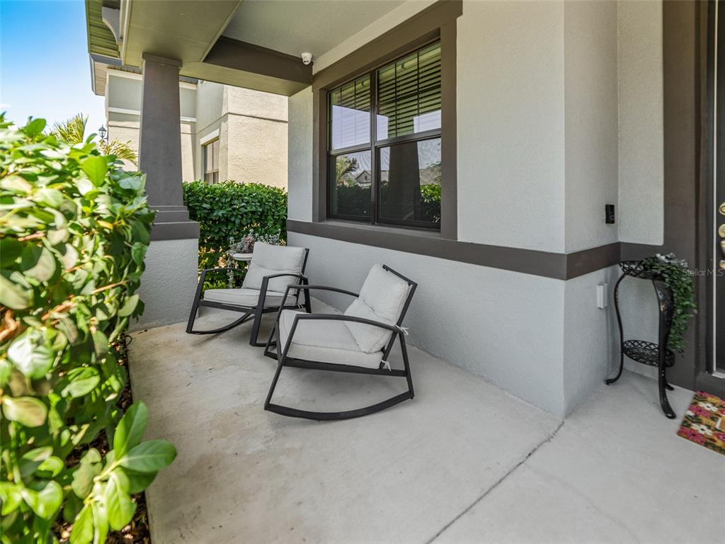 A covered front porch features two rocking chairs, a small side table, and a plant stand — 1220 FLORABLU DRIVE, SEFFNER, FL