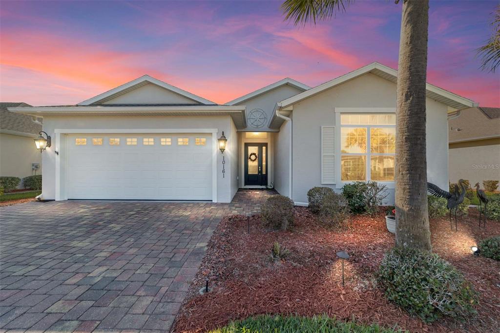A single-story house with a paved driveway, two-car garage, and a landscaped front yard — 10161 JULIA ISLES AVENUE, OXFORD, FL