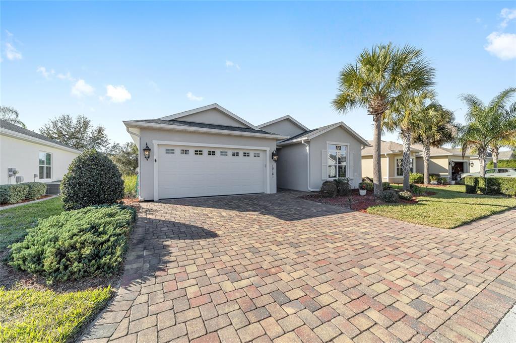 A single-story house with a paved driveway, a two-car garage, and palm trees — 10161 JULIA ISLES AVENUE, OXFORD, FL