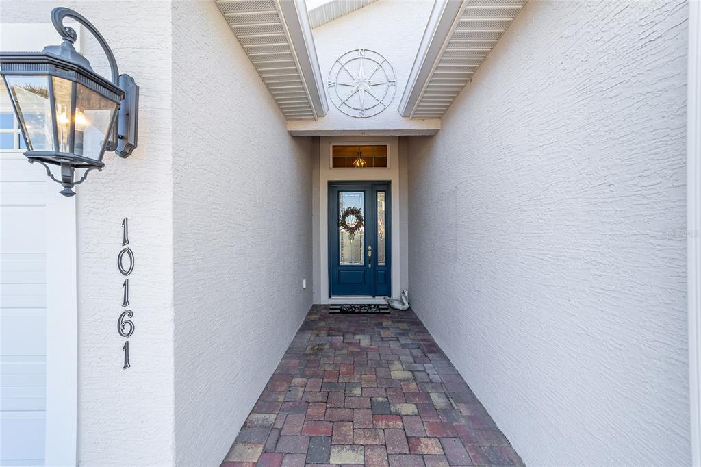 A paved walkway leads to a blue front door under a covered entryway — 10161 JULIA ISLES AVENUE, OXFORD, FL