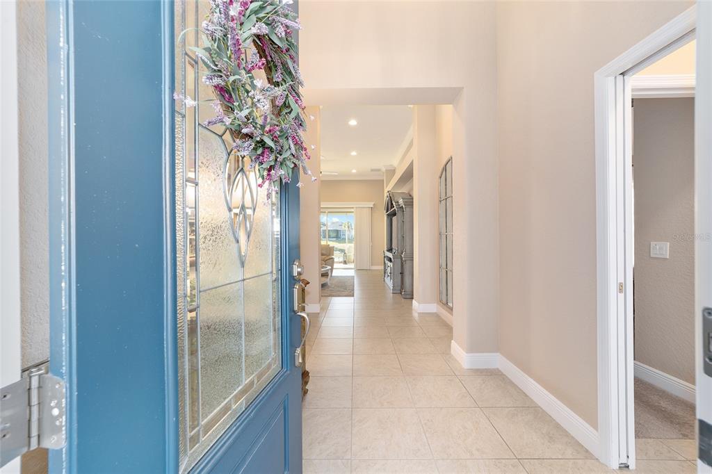 A view from a blue front door into a tiled foyer leading to a living area — 10161 JULIA ISLES AVENUE, OXFORD, FL