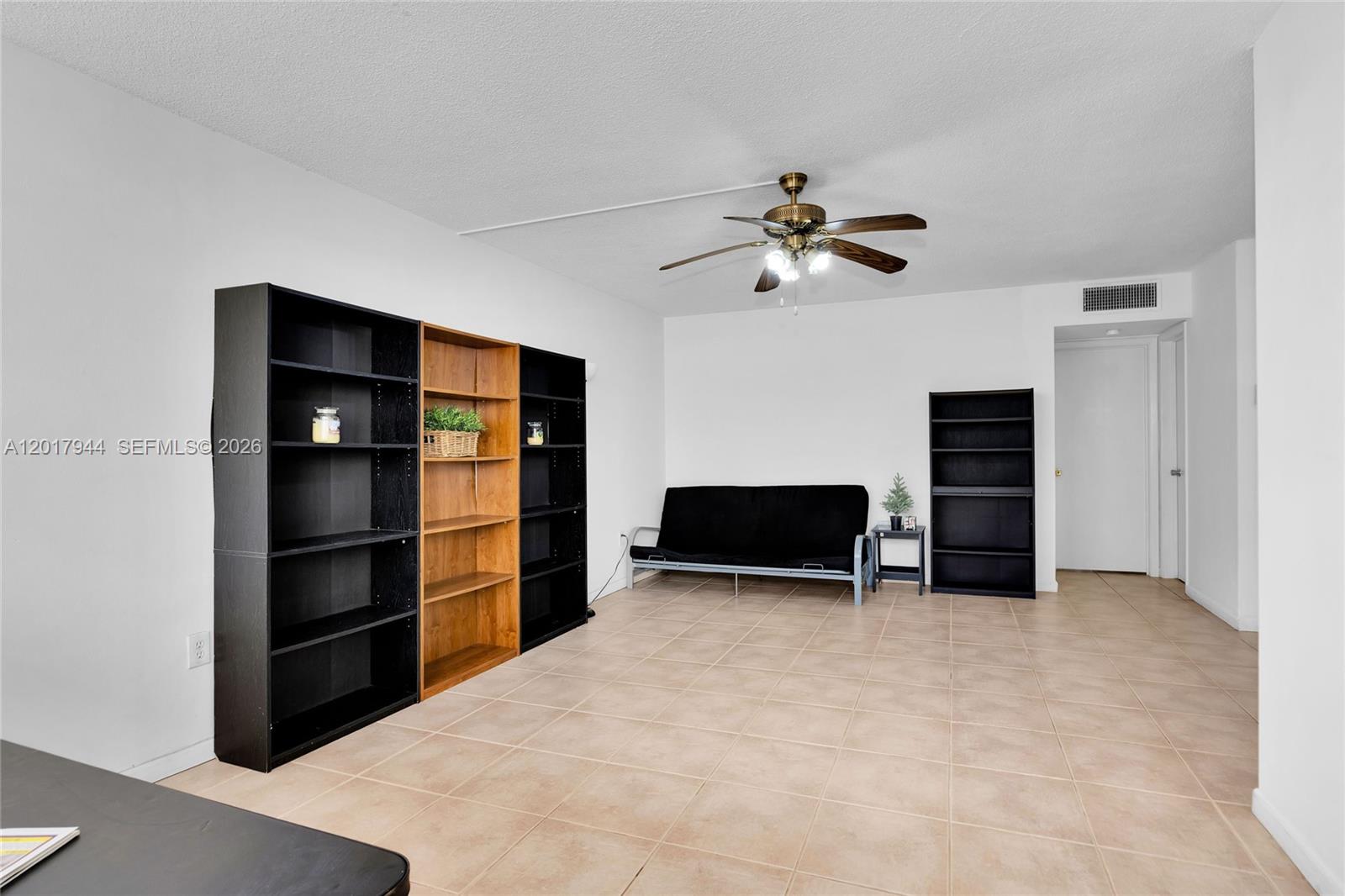 A living room features tile flooring, a black futon, and several tall shelving units — 12590 NE 16th Ave # 208, North Miami FL 33161, NORTH MIAMI, FL