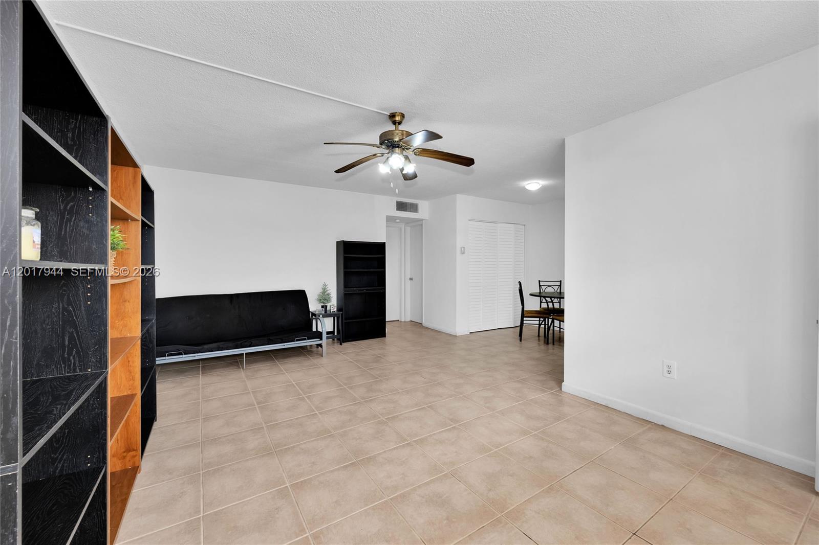 A living room features tile flooring, a ceiling fan, and a black futon — 12590 NE 16th Ave # 208, North Miami FL 33161, NORTH MIAMI, FL