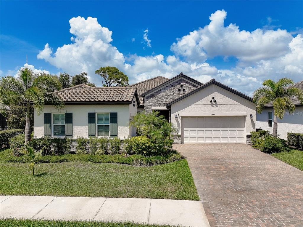 A single-story house with a stone facade, tile roof, and a paved driveway — 11484 MONTSERRAT DRIVE, VENICE, FL
