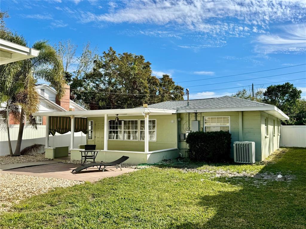 A light green house features a covered patio, a paved area, and a grassy backyard — 185 22ND AVENUE N, ST PETERSBURG, FL