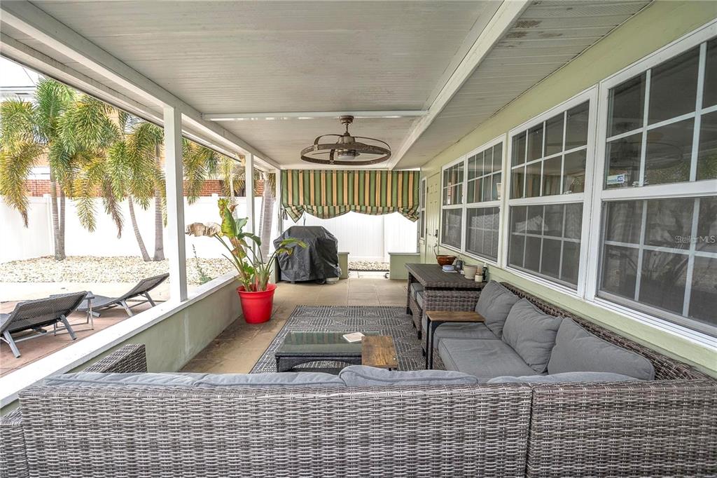 A covered patio features wicker furniture, a ceiling fan, and a view of a backyard — 185 22ND AVENUE N, ST PETERSBURG, FL