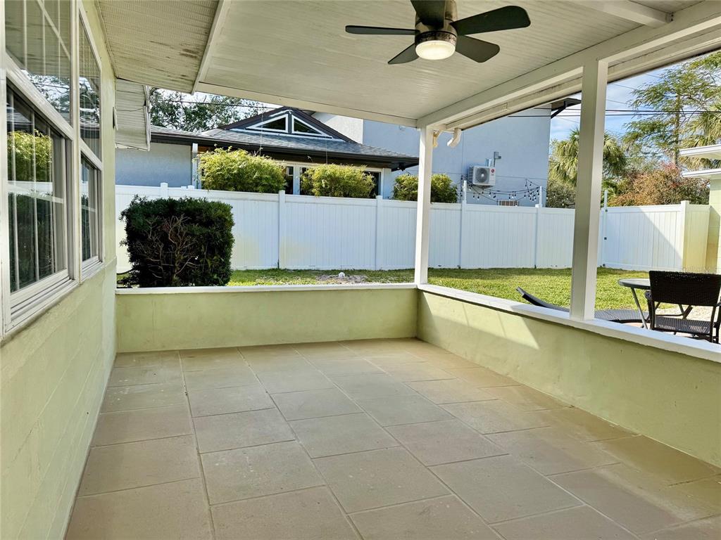A covered patio with light-colored tile flooring, a ceiling fan, and a white privacy fence — 185 22ND AVENUE N, ST PETERSBURG, FL