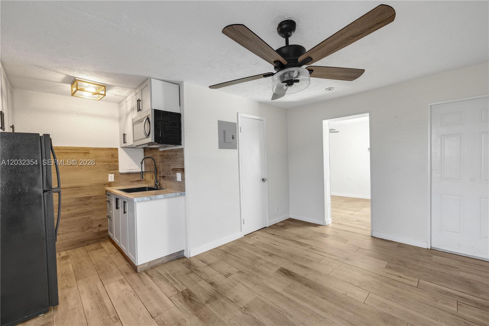 A small kitchen area features white cabinets, wood-look backsplash, and a ceiling fan — HOLLYWOOD, FL