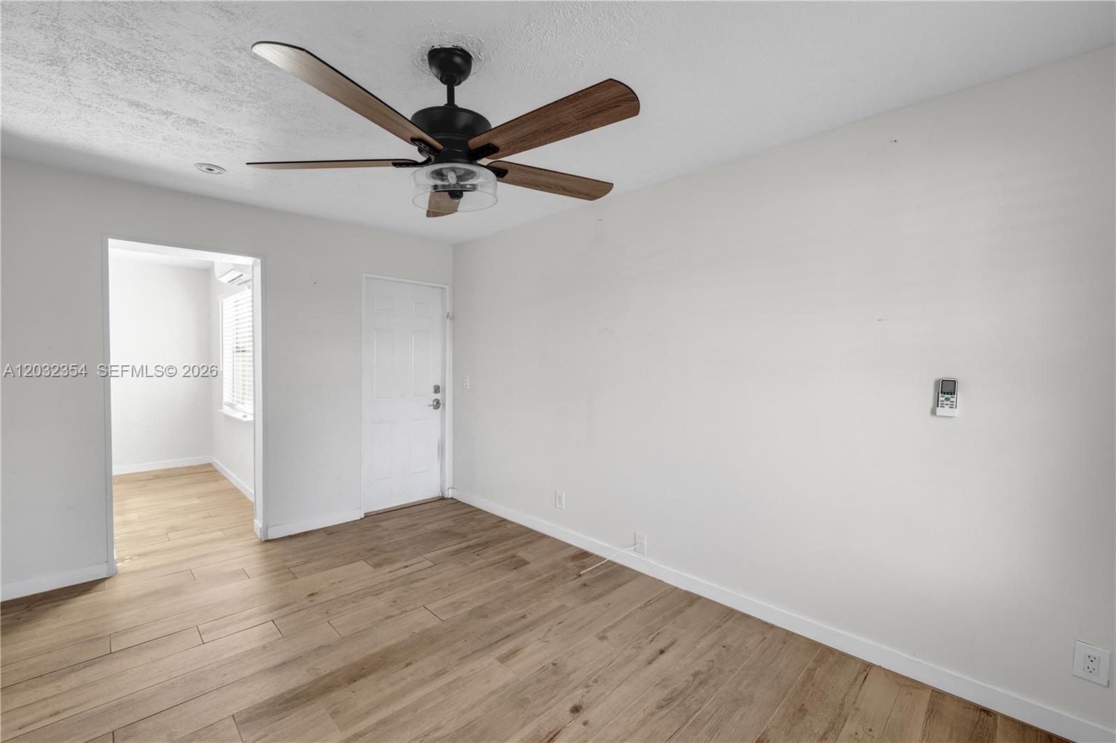 A room with light wood-look flooring, a ceiling fan, and a white door — HOLLYWOOD, FL