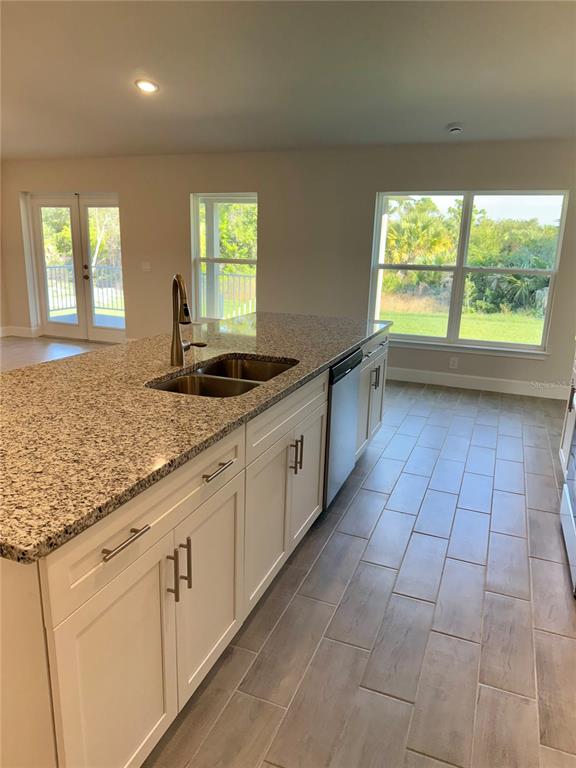 A kitchen island with a granite countertop and sink sits in front of large windows — 9527 IMPALA CIRCLE, PORT CHARLOTTE, FL