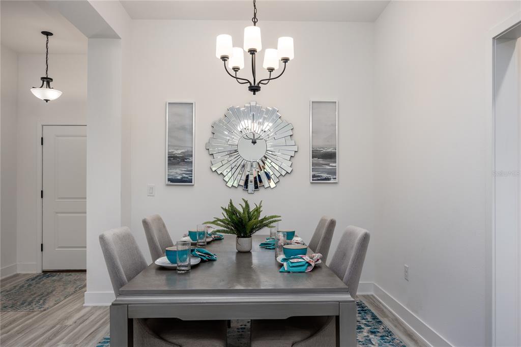 A dining room features a gray table, upholstered chairs, a sunburst mirror, and a chandelier — 13622 NW 150TH CIRCLE, ALACHUA, FL