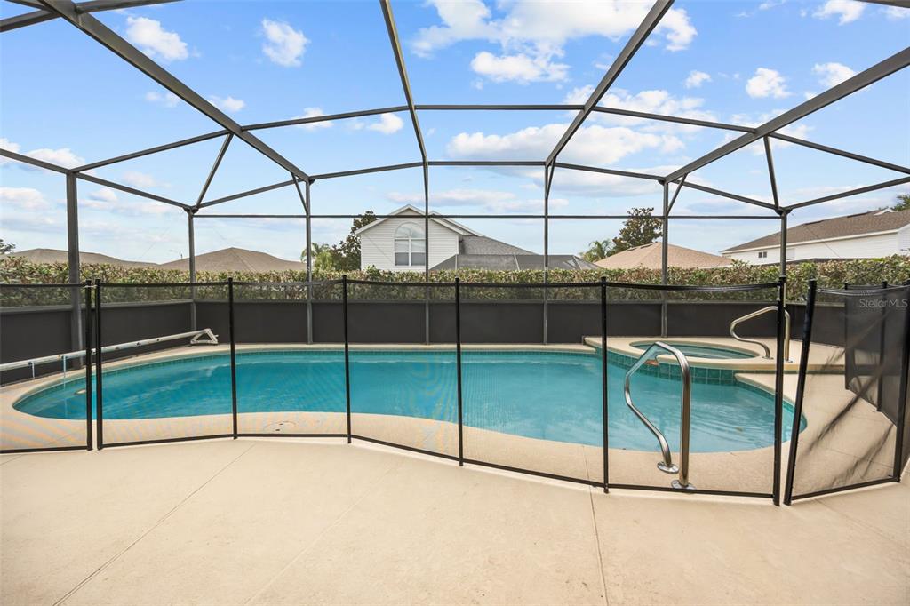 A screened-in swimming pool and spa with a safety fence on a concrete patio — 2254 WYNDHAM PALMS WAY, KISSIMMEE, FL