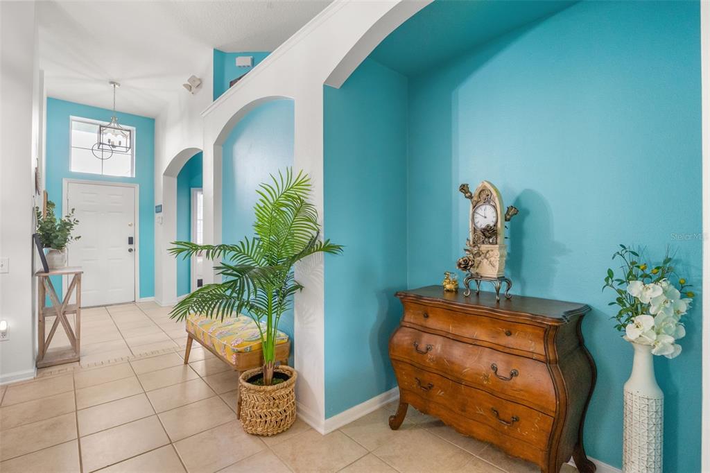 A foyer features turquoise walls, tile flooring, a wooden chest, and a potted palm plant — 2254 WYNDHAM PALMS WAY, KISSIMMEE, FL