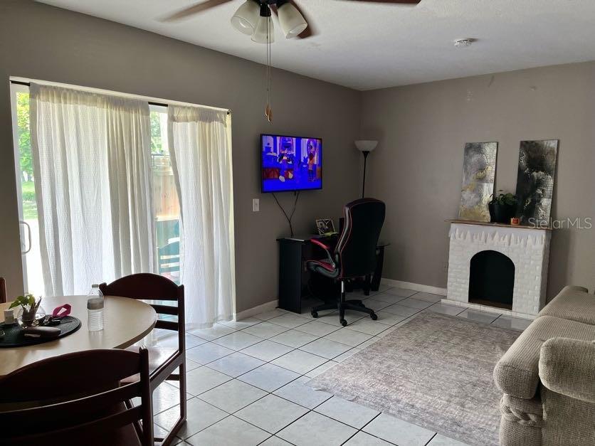 A living room features tile flooring, a dining area, a desk, and a decorative fireplace — 5885 DAHLIA DRIVE UNIT 31/116, ORLANDO, FL
