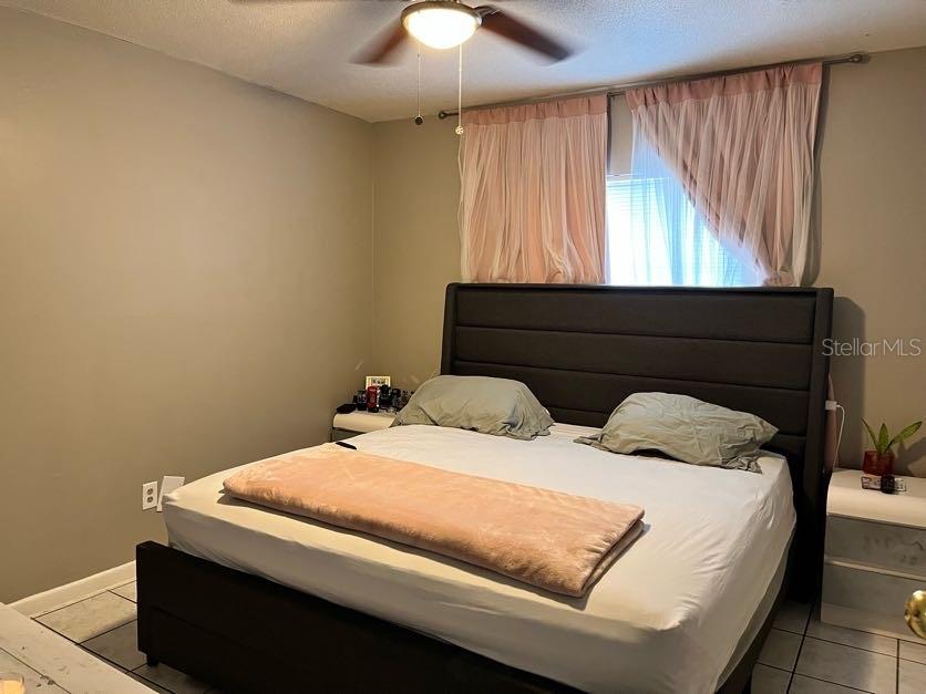 A bedroom features a dark upholstered headboard, a bed with light bedding, and pink curtains — 5885 DAHLIA DRIVE UNIT 31/116, ORLANDO, FL