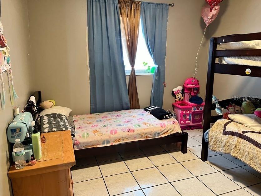 A bedroom features a twin bed, a bunk bed, and a wooden dresser on tiled flooring — 5885 DAHLIA DRIVE UNIT 31/116, ORLANDO, FL