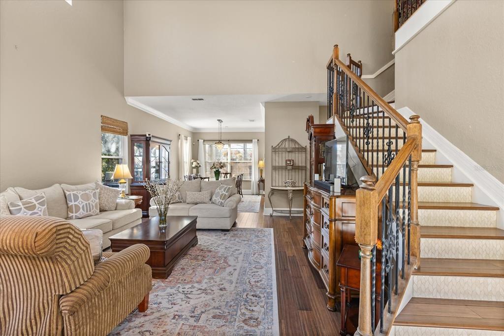 A living room with a staircase, hardwood floors, and an area rug in an open layout — 2450 DAHLGREN WAY, WINTER GARDEN, FL