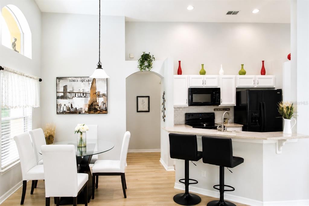 A dining area with a glass table and white chairs sits beside a kitchen — 2520 DHARMA CIRCLE, KISSIMMEE, FL