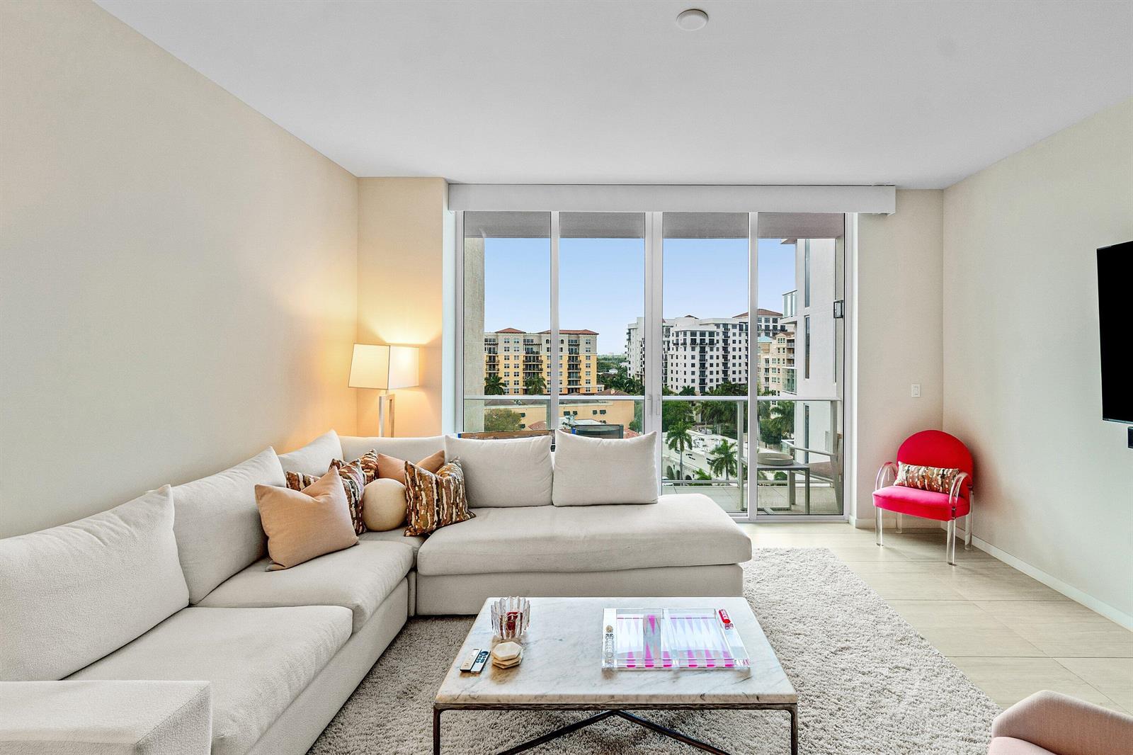 A living room features a large sectional sofa, marble coffee table, and floor-to-ceiling windows — 200 SE Mizner Boulevard # 810, Boca Raton FL 33432, BOCA RATON, FL