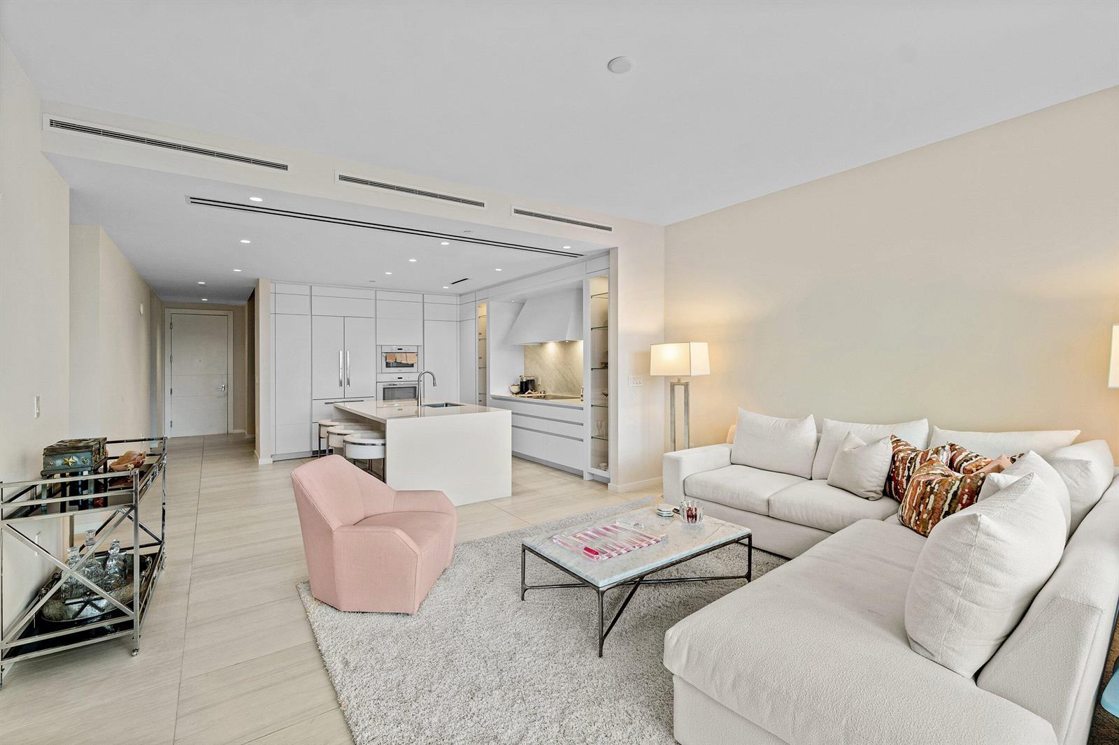 A modern open-concept living room and kitchen featuring white cabinetry, a sectional, and tile flooring — 200 SE Mizner Boulevard # 810, Boca Raton FL 33432, BOCA RATON, FL