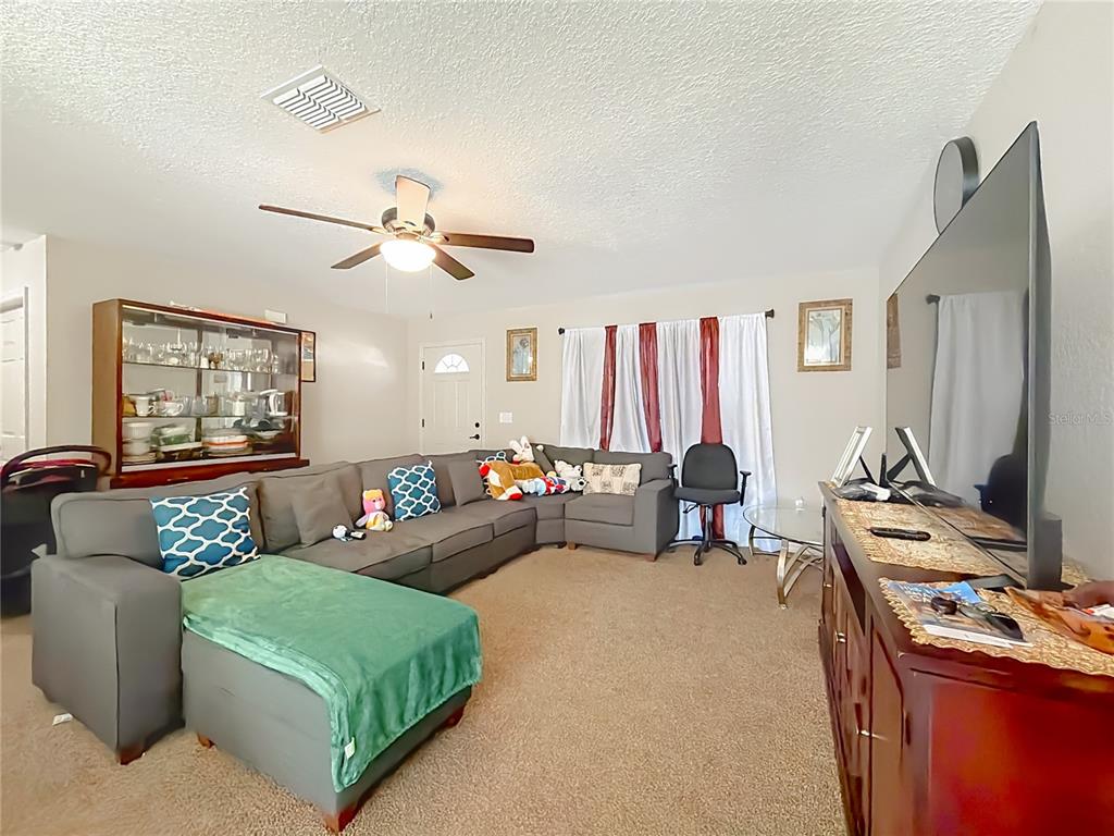 A living room features a large gray sectional sofa, a television, and a china cabinet — 14321 SW 79TH TERRACE, OCALA, FL