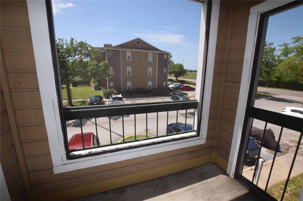 A view from a screened-in balcony overlooking a parking lot and a multi-story apartment building — 5533 CHRISHIRE WAY UNIT F201, ORLANDO, FL