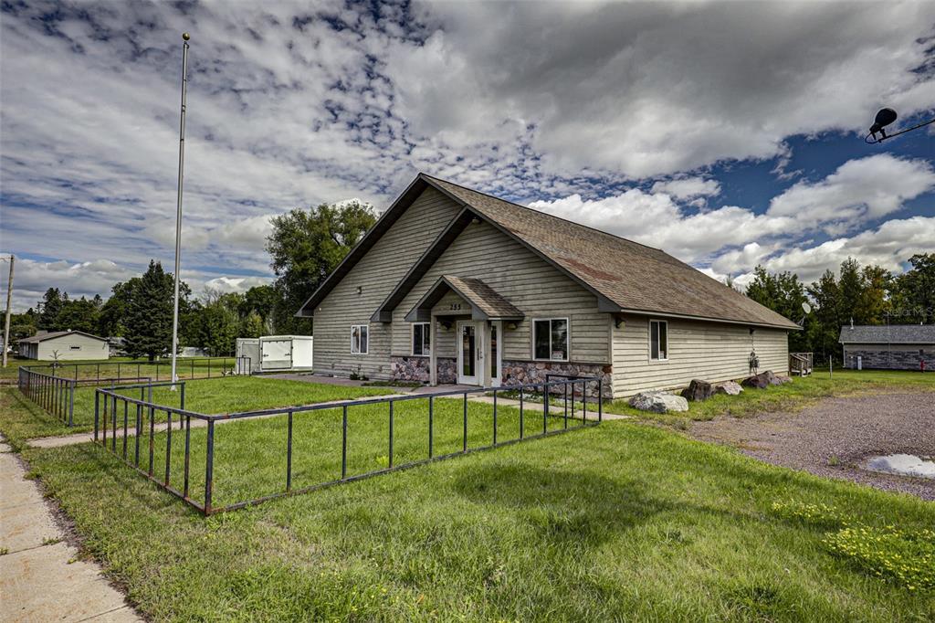 A single-story building with light-colored siding and a stone base features a gabled roof — 255 FAIR AVENUE, MARENISCO, MI