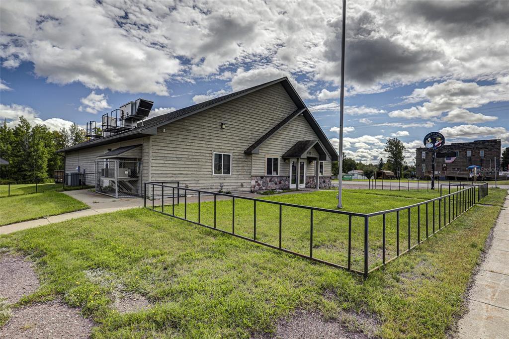 A light-colored, single-story building with a metal roof stands behind a black metal fence — 255 FAIR AVENUE, MARENISCO, MI