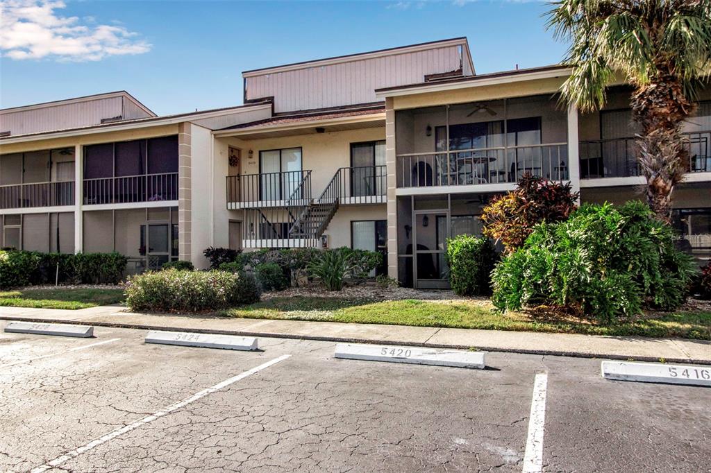 A two-story apartment building with screened balconies and numbered parking spaces in the foreground — 5420 SWIFT ROAD UNIT 38, SARASOTA, FL