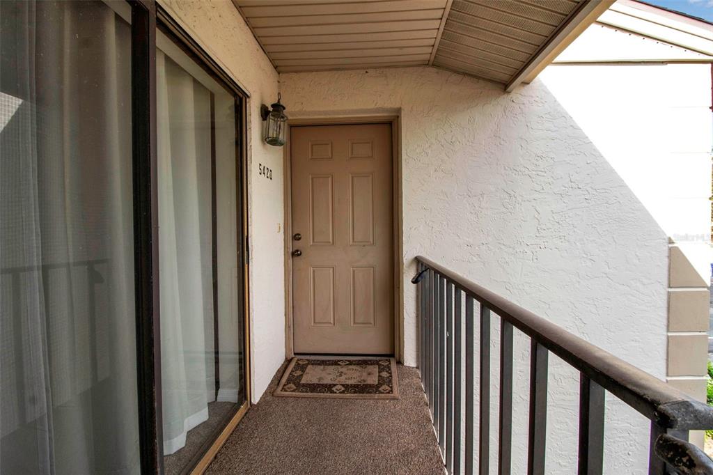 An exterior view of a building entrance with a door, sliding glass door, and railing — 5420 SWIFT ROAD UNIT 38, SARASOTA, FL