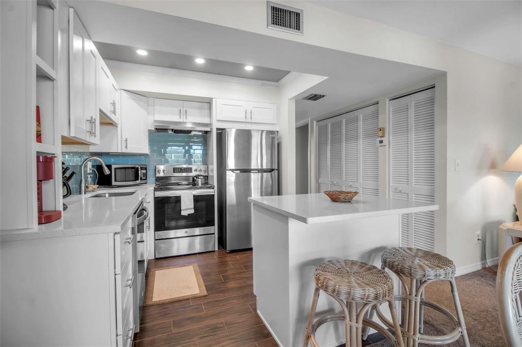 A kitchen with white cabinets, stainless steel appliances, a breakfast island, and dark wood flooring — 5420 SWIFT ROAD UNIT 38, SARASOTA, FL