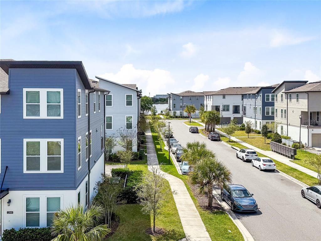 An exterior view of a residential street lined with modern multi-story townhomes and parked cars — 12905 GABOR AVENUE, ORLANDO, FL