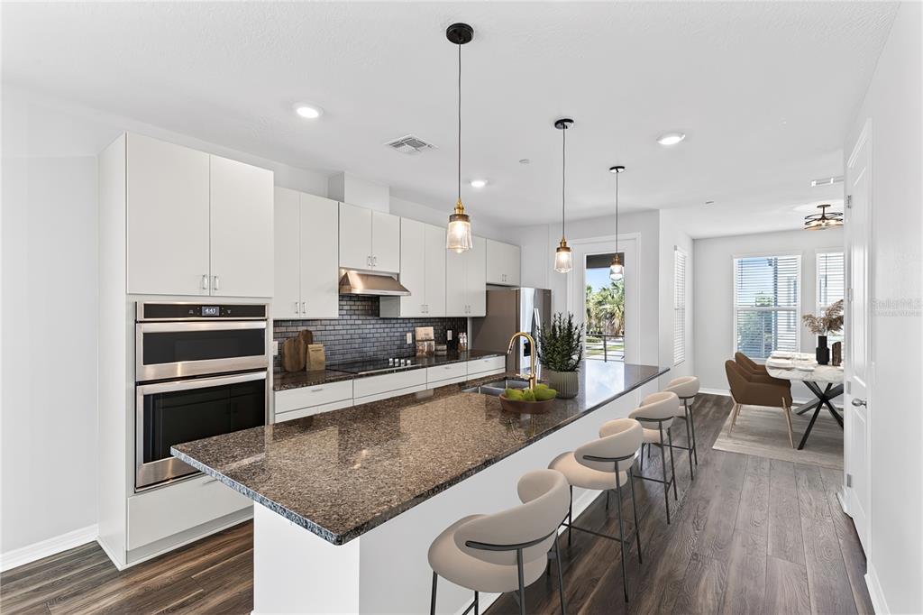 A modern kitchen features white cabinetry, granite countertops, a large island, and stainless steel appliances — 12905 GABOR AVENUE, ORLANDO, FL