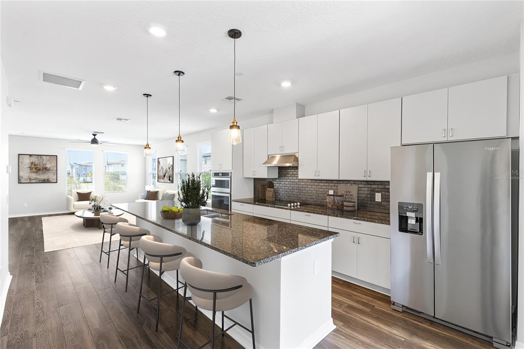 A modern kitchen features white cabinets, granite countertops, a large island, and stainless steel appliances — 12905 GABOR AVENUE, ORLANDO, FL