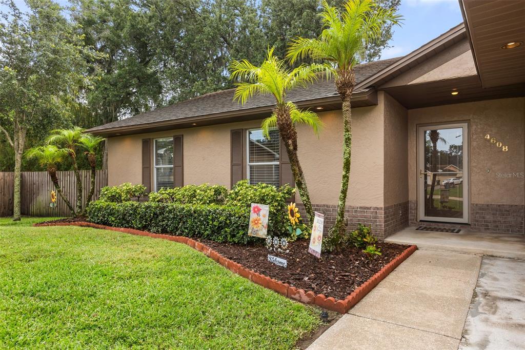 A single-story house exterior features a tan stucco facade, brick accents, and a landscaped front yard — 4608 STURBRIDGE COURT, ORLANDO, FL