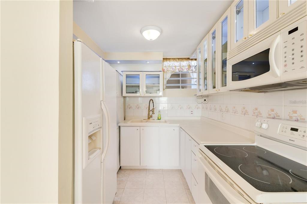 A white kitchen features white cabinets, a glass-top stove, and a white refrigerator — 5890 JOSE M TARTAK AVE UNIT 704A, CAROLINA, PR