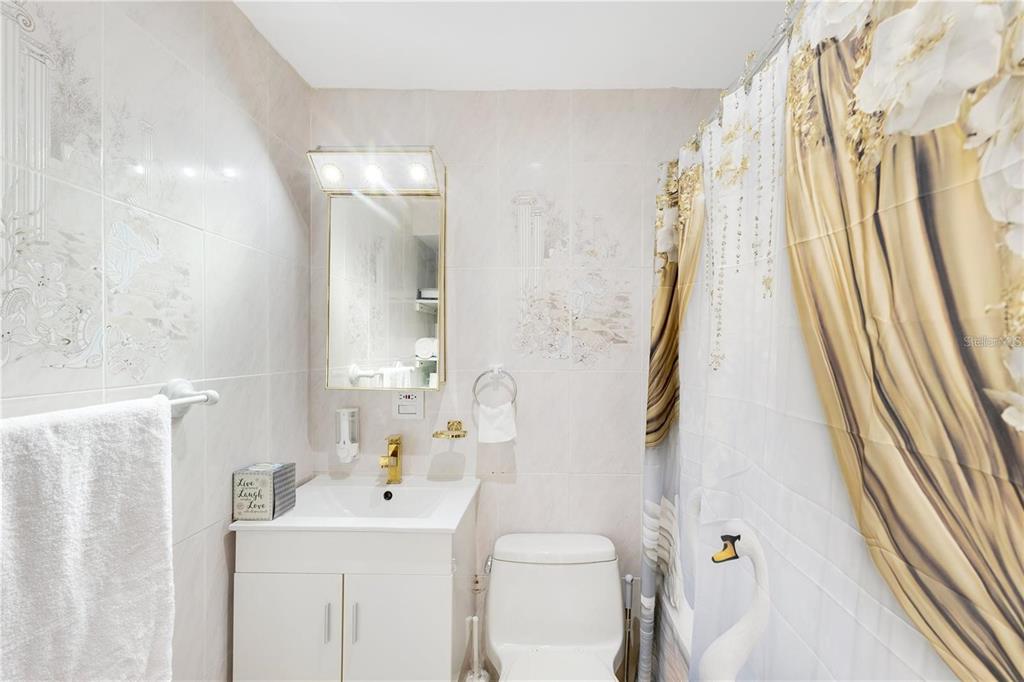 A small bathroom features a white vanity, a gold faucet, and a decorative shower curtain — 5890 JOSE M TARTAK AVE UNIT 704A, CAROLINA, PR